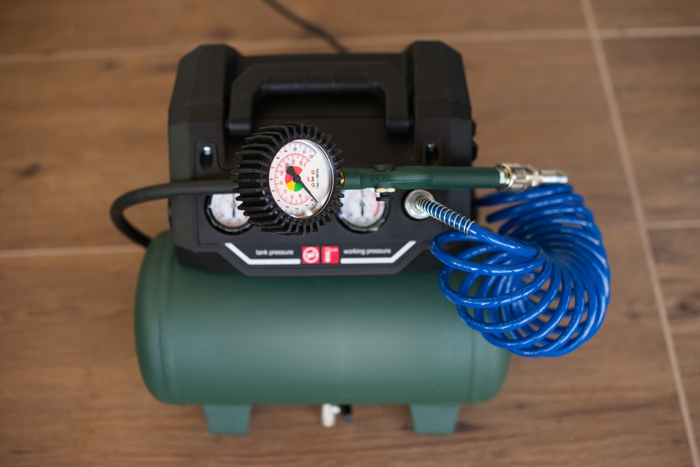 Green,air,compressor,with,pressure,gauge,connected,to,a,compressor